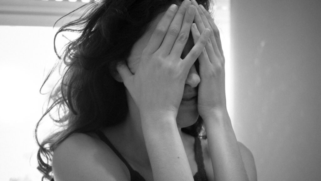Mujer cubriéndose el rostro con ambas manos en gesto de angustia. Fotografías de Mora Lopez